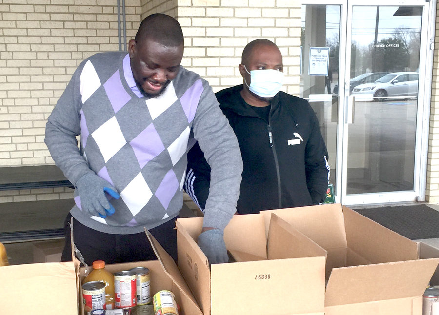 Yemi Salud volunteers at his church's food drive, packing food into boxes to hand out to families. 