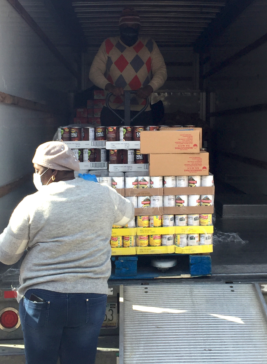 Volunteers unload pallets of food from a moving truck for their church food drive through.