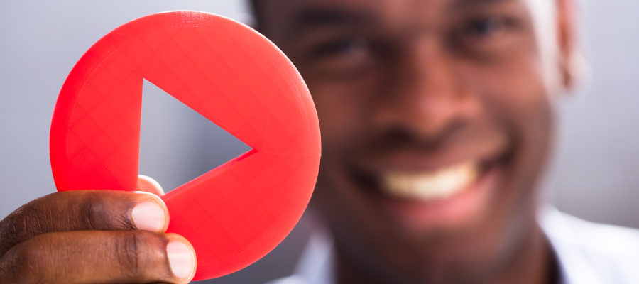 African American Man holding a red paper youtube play button and smiling