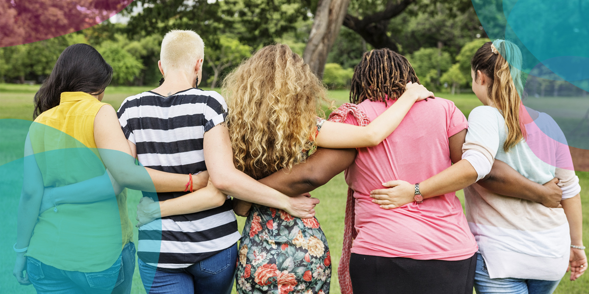 A diverse group of women stand arm in arm with their backs to the camera.