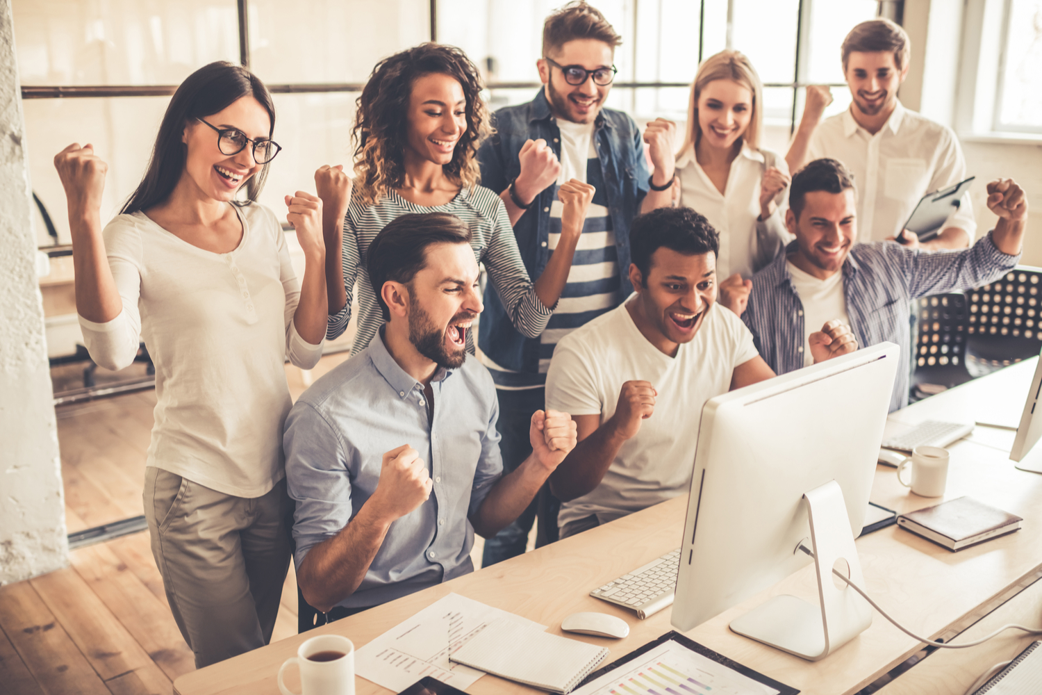 What to Look for When Tracking Your Online Donations, a team of people gathered around a computer, working on a project.