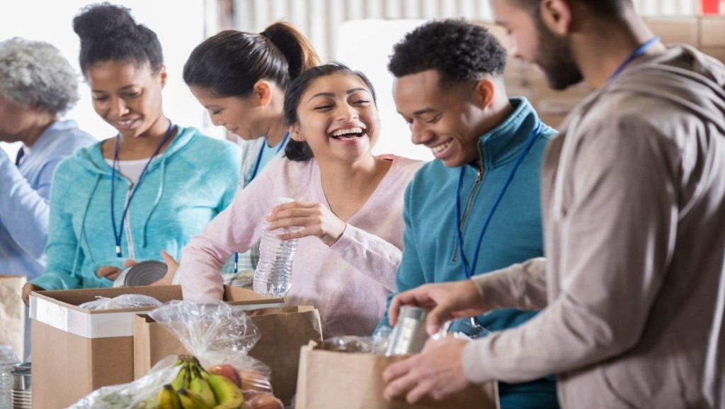 volunteers laughing while packing food for a charity