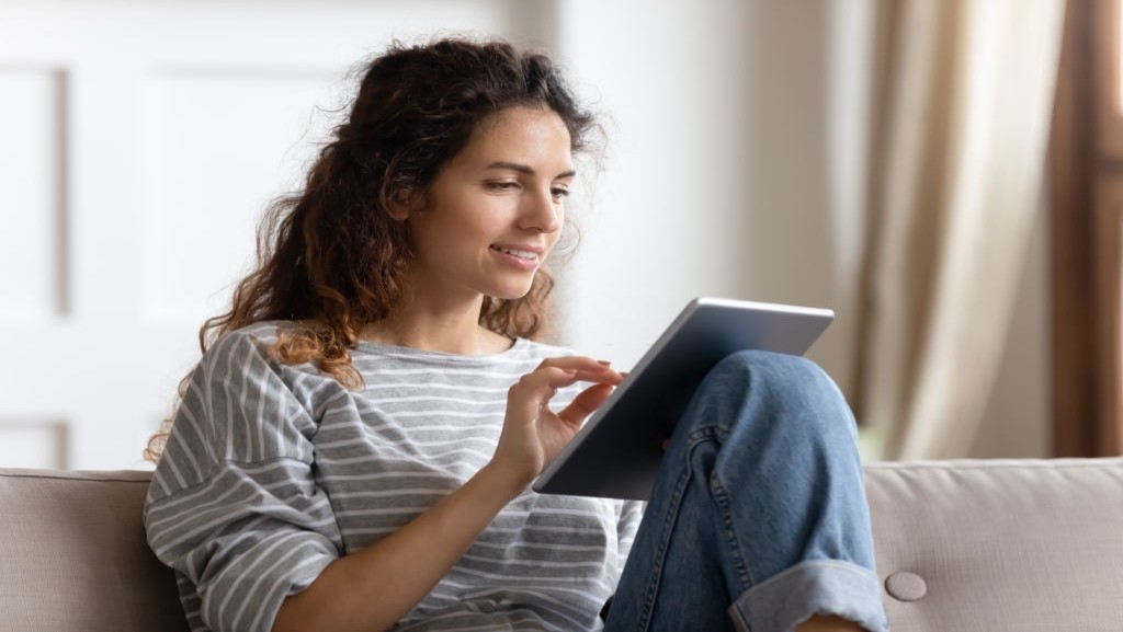 women reading a tablet while sitting on a couch