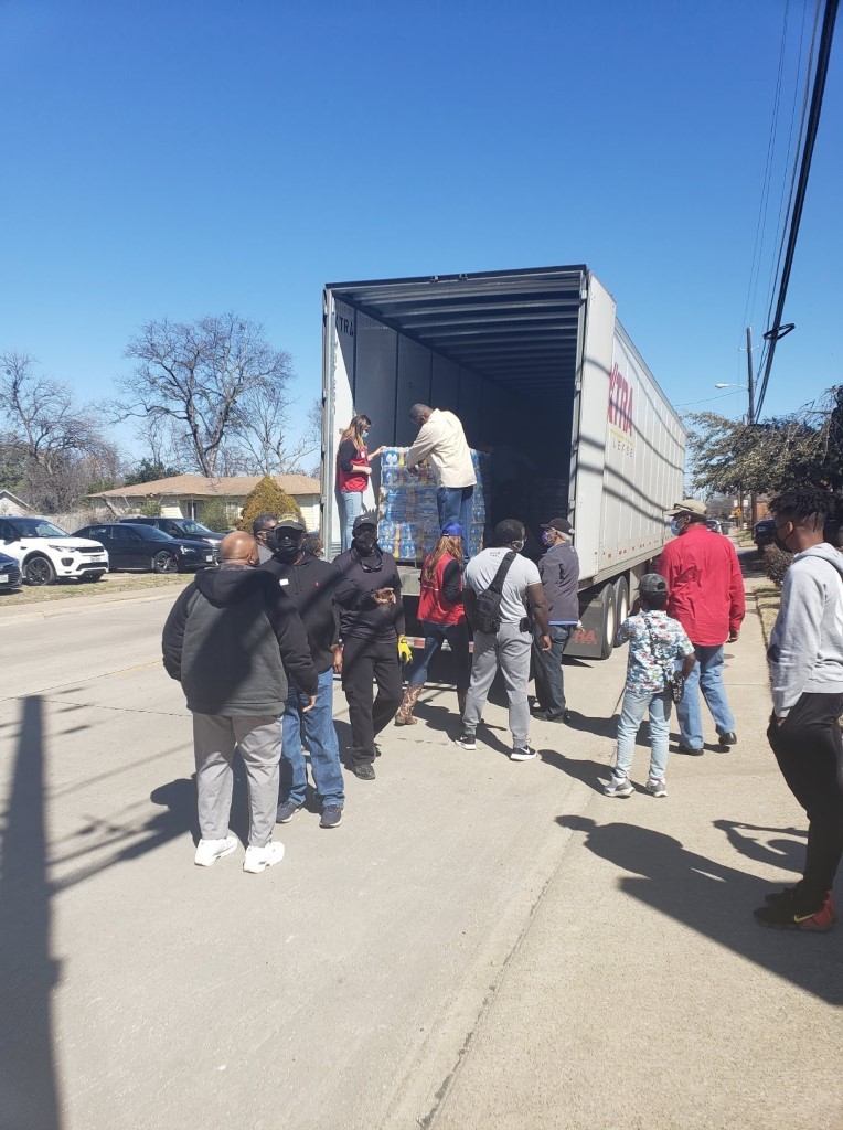A group of people standing around a truck
Description automatically generated with low confidence