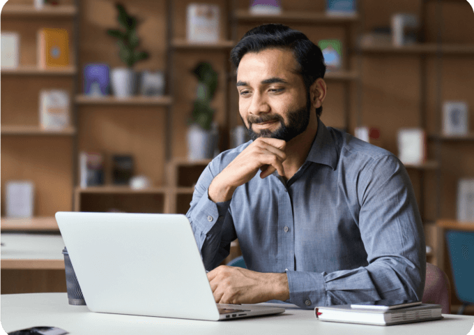 man sitting at a desk looking at a laptop
