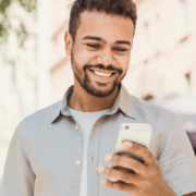 man standing outside smiling while looking at his phone