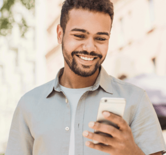 man standing outside smiling while looking at his phone