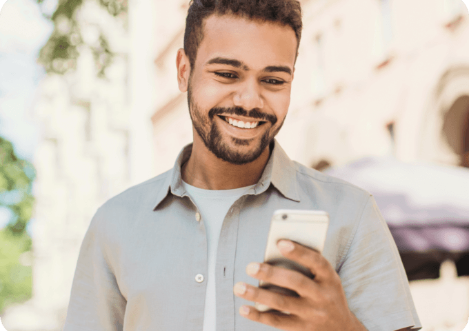 man standing outside smiling while looking at his phone