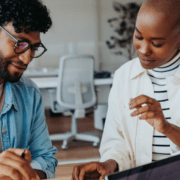A woman and a man sitting at a table and looking down at a paper