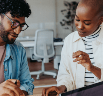 A woman and a man sitting at a table and looking down at a paper