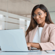 A woman sitting at a desk looking at a laptop