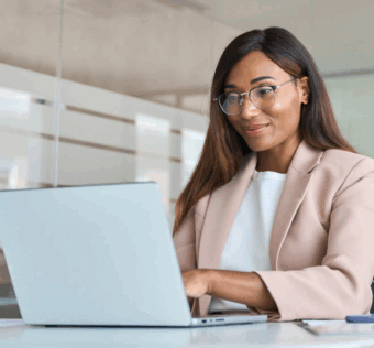 A woman sitting at a desk looking at a laptop