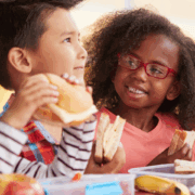 young children smiling and eating lunch at school